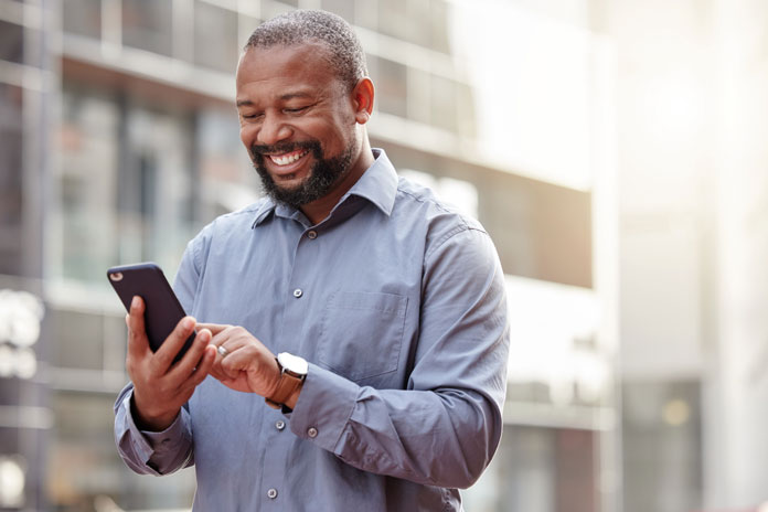 Networking - Mann schaut unterwegs auf sein Smartphone und networked mit seinen Kollegen