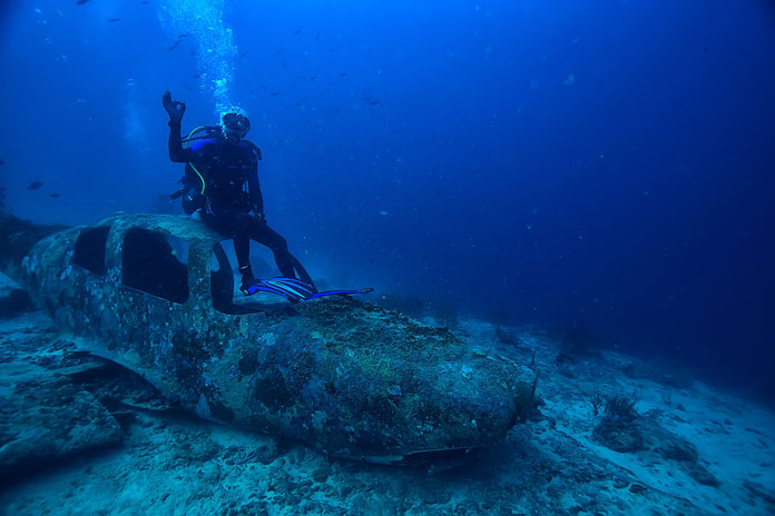 Bermudadreieck Taucher sitzt im Meer auf abgestürztem Flugzeug